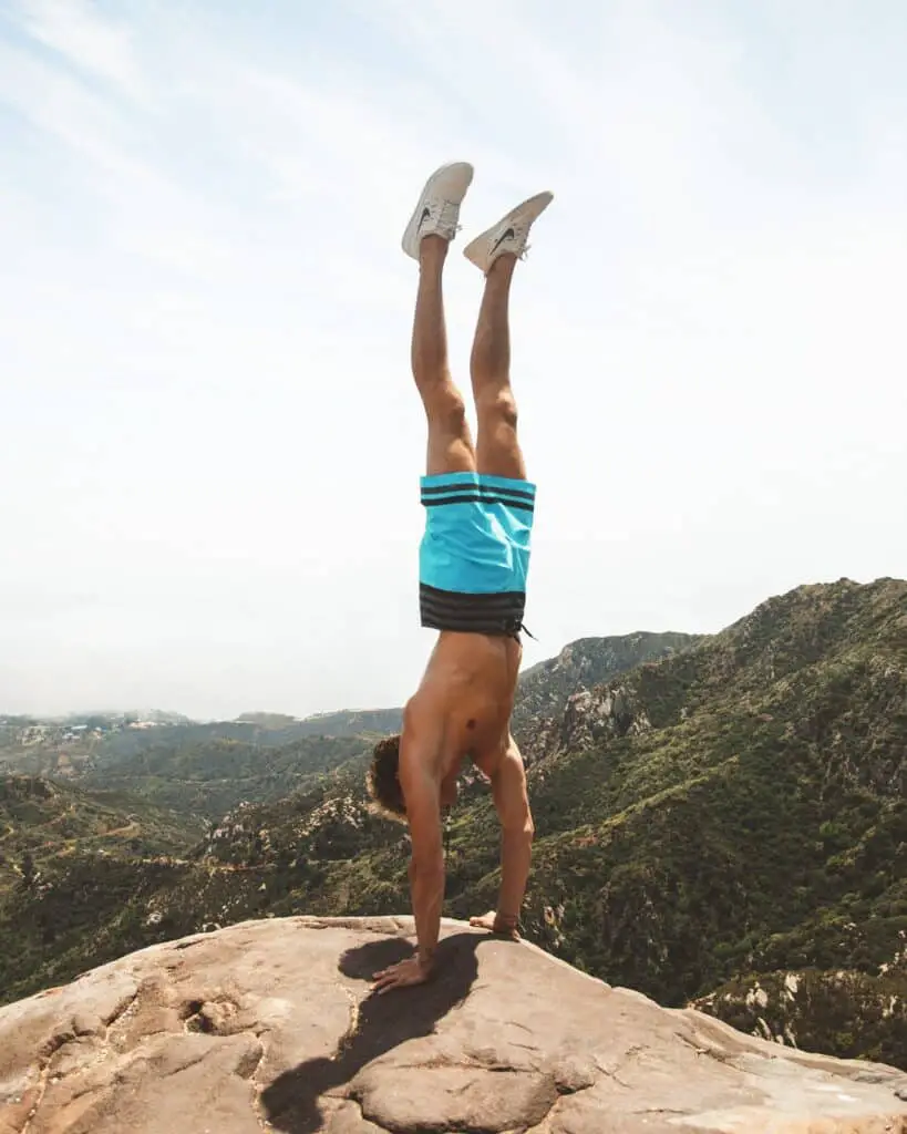 Man doing hand push up at the top of the mountain