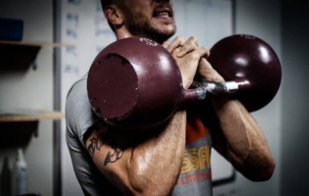 Men in gym lifting kettle bell