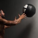 Male Athlete Crouched Doing Wall Balls Exercises At The Gym