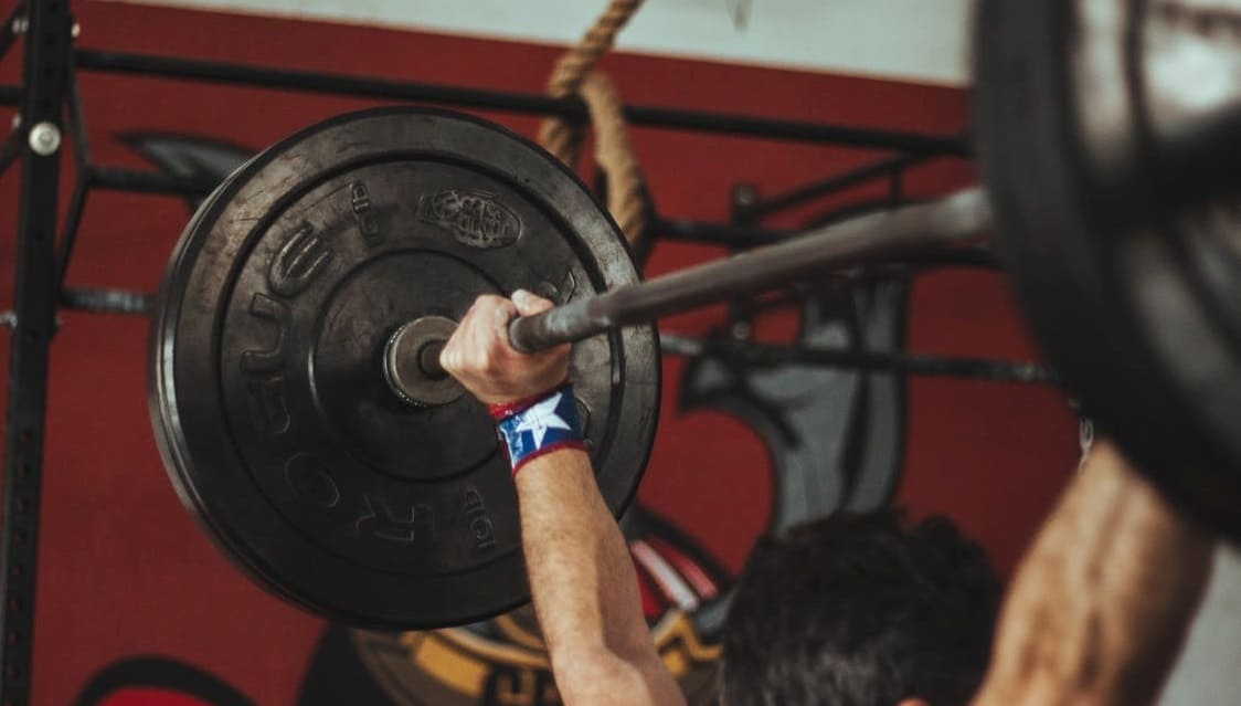 Person carrying a black barbell