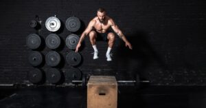 dedicated serious active strong fit sweaty muscular man with big muscles doing box jump workout in the gym