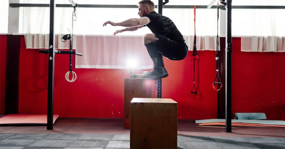 young man jumping onto a box as part of exercise routine